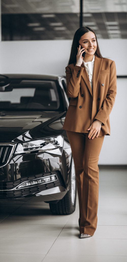 Young beautiful woman choosing car in a car showroom